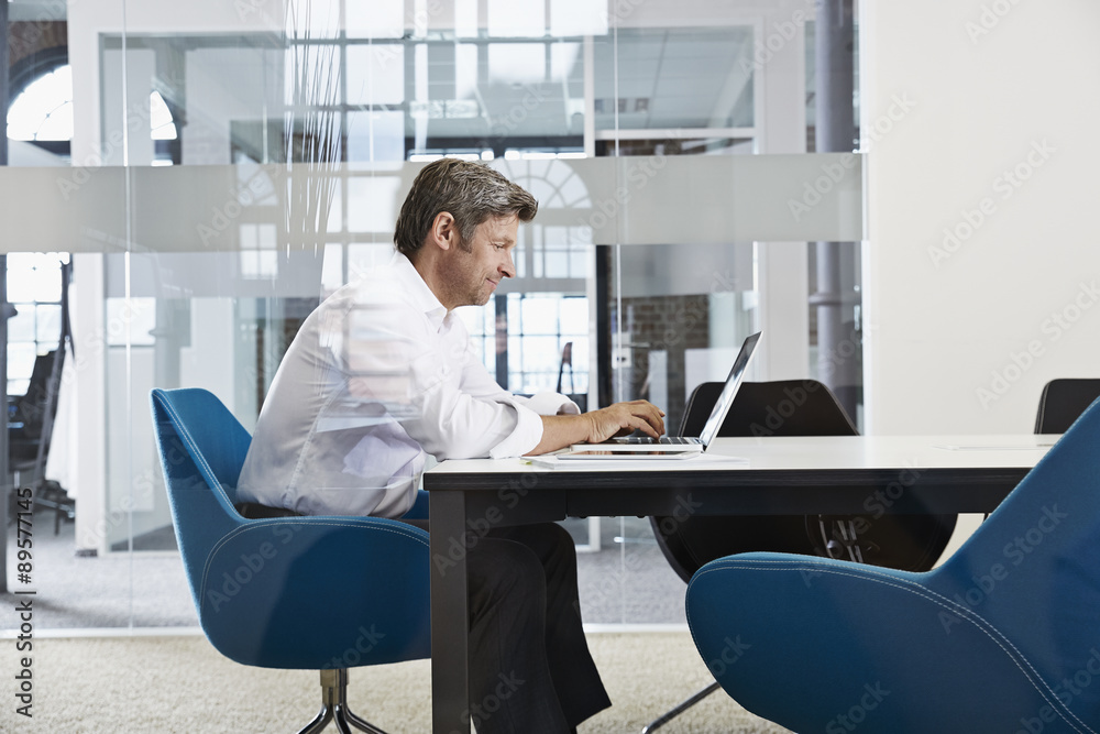 Businessman using laptop in conference room Businessman using laptop in conference room