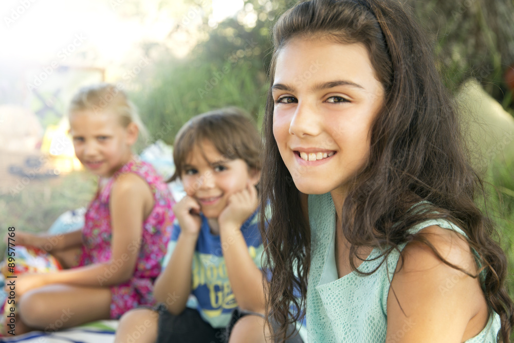 Portrait of smiling girl outdoors with siblings in background Portrait of smiling girl outdoors with siblings in background