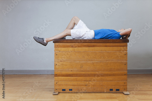 Germany, Berlin, Young man lying on vaulting horse