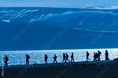 Silhouetted group of hikers in Barentsoya, Svalbard, Norway. photo