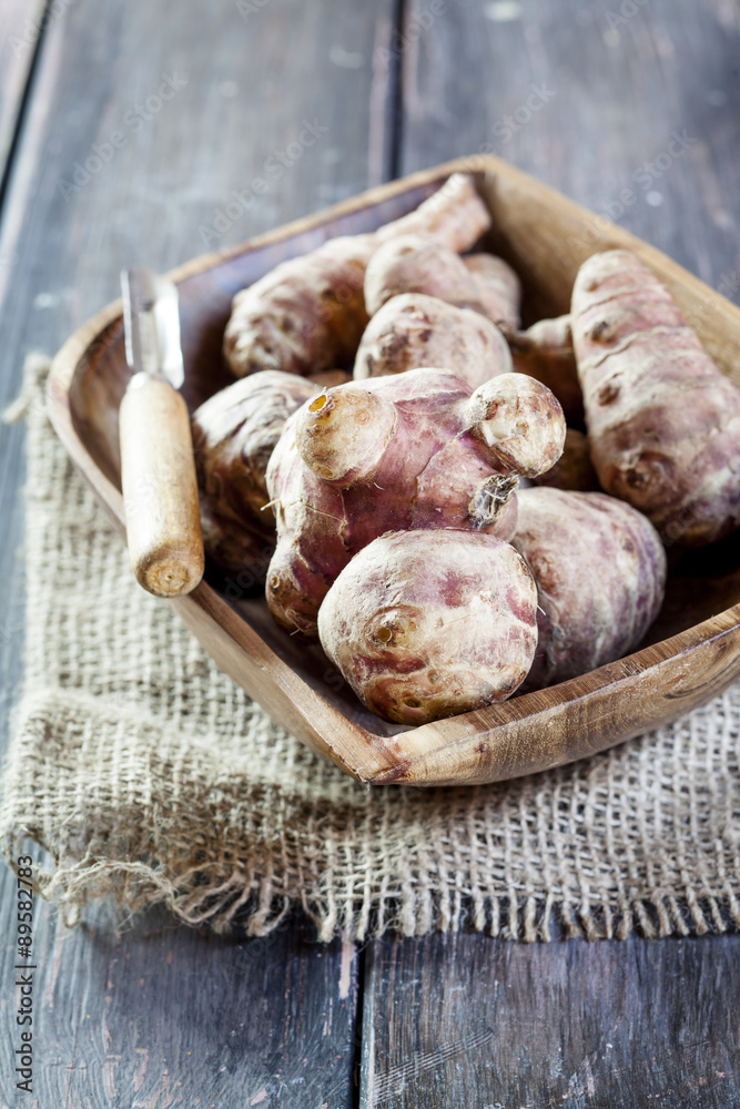 Bowl of Jerusalem artichokes and peeler Bowl of Jerusalem artichokes and peeler