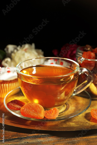 Composition with cup of herbal tea, dried apricots and peony flowers on wooden background