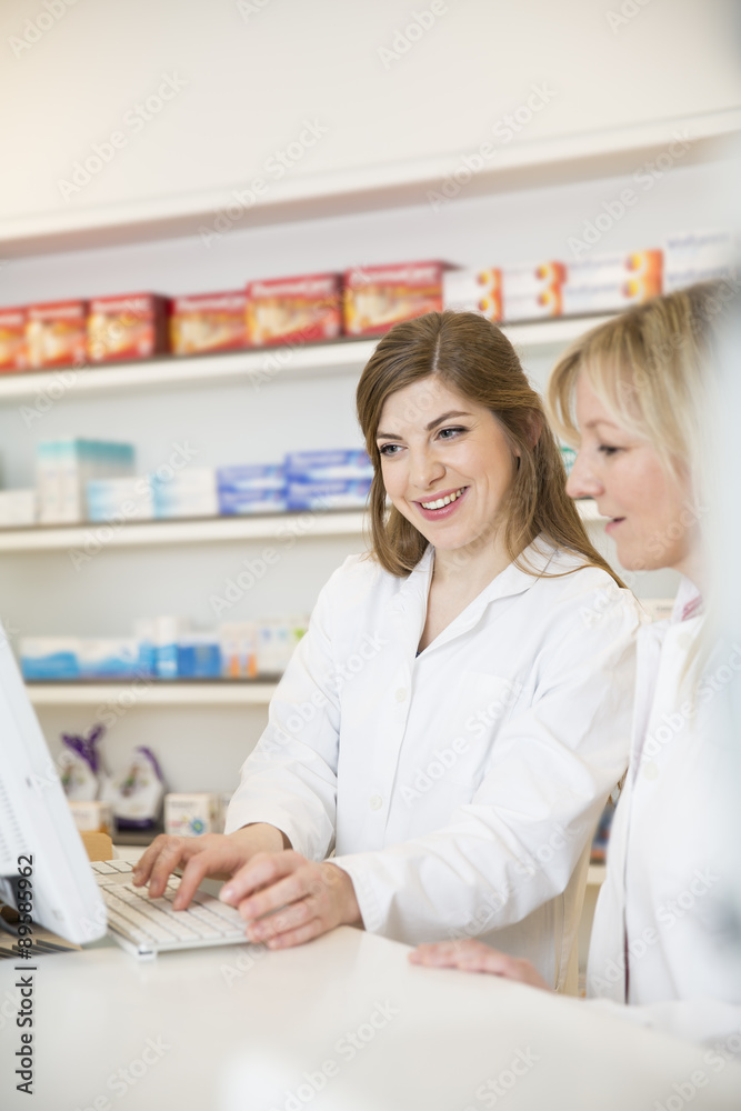Two female pharmacists looking at computer screen Two female pharmacists looking at computer screen