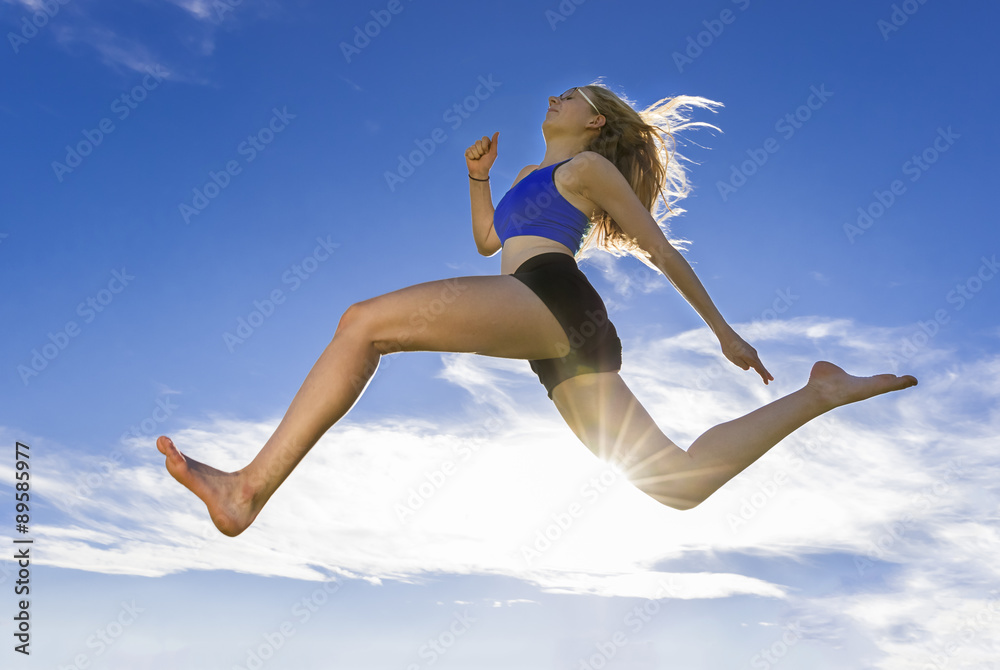 Young athlete jumping under blue sky