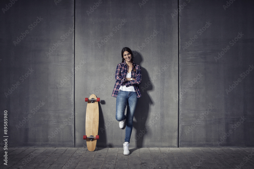 Young woman standing besides her longboard Young woman standing besides her longboard