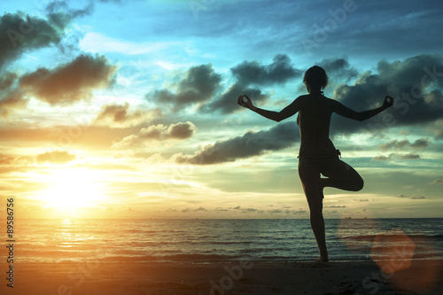 Silhouette of woman standing at yoga pose on the beach during an amazing sunset. Meditation  balance  harmony and tranquility concept.