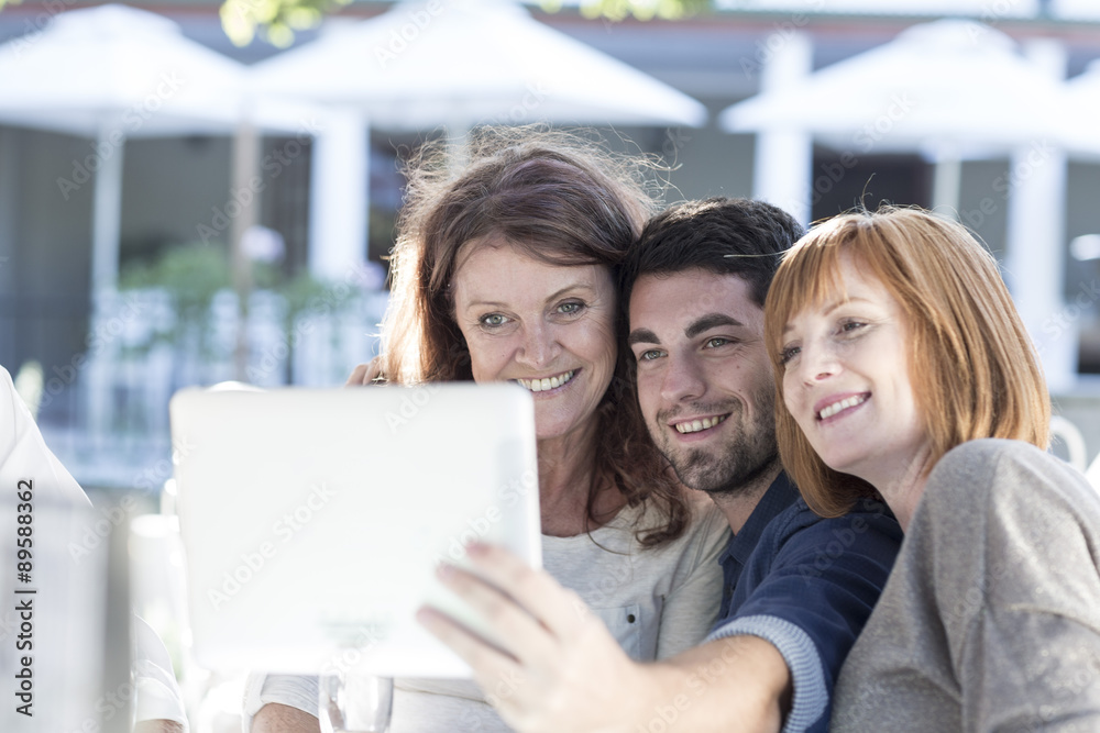Three people at a restaurant taking a photograph with digital tablet Three people at a restaurant taking a photograph with digital tablet