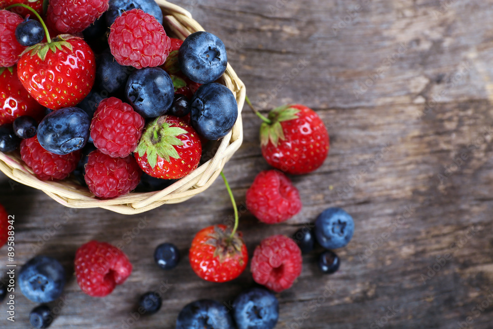 Sweet tasty berries in basket on wooden table close up Sweet tasty berries in basket on wooden table close up