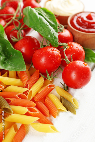 Pasta penne with tomatoes, cheese and basil on color wooden background