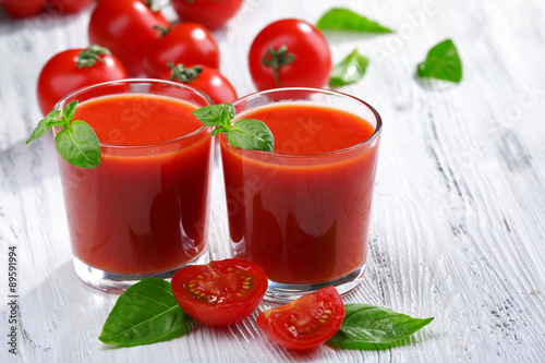 Glasses of tomato juice on wooden table, closeup