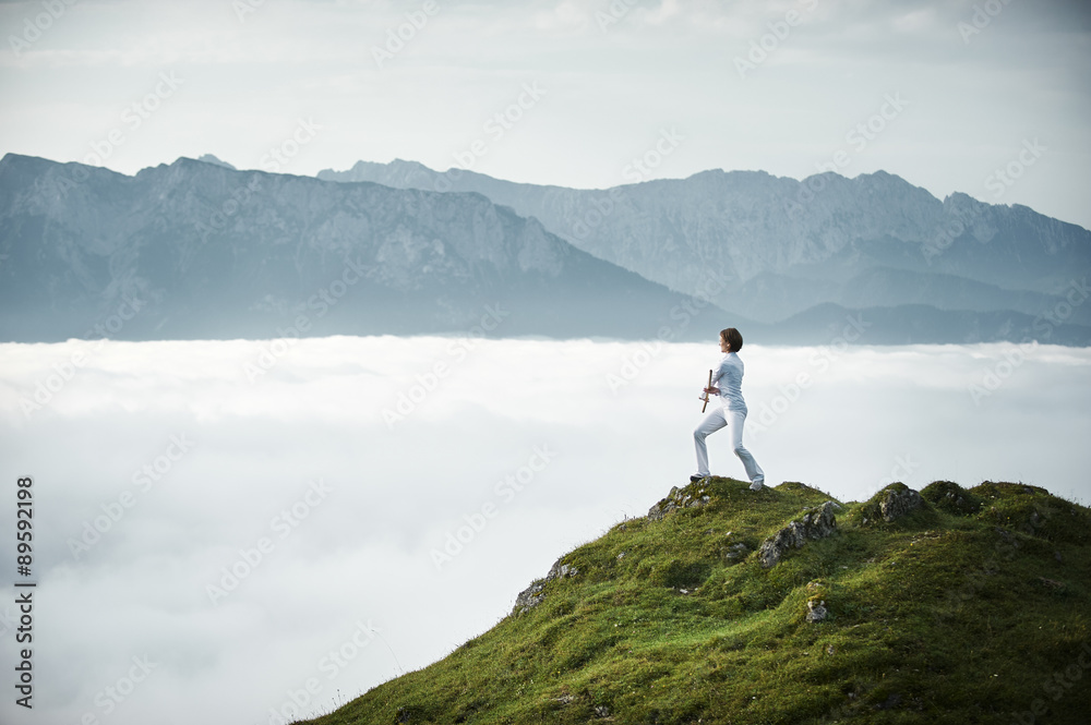 Austria, Kranzhorn, Mid adult woman exercising stick fighting on mountain top Austria, Kranzhorn, Mid adult woman exercising stick fighting on mountain top