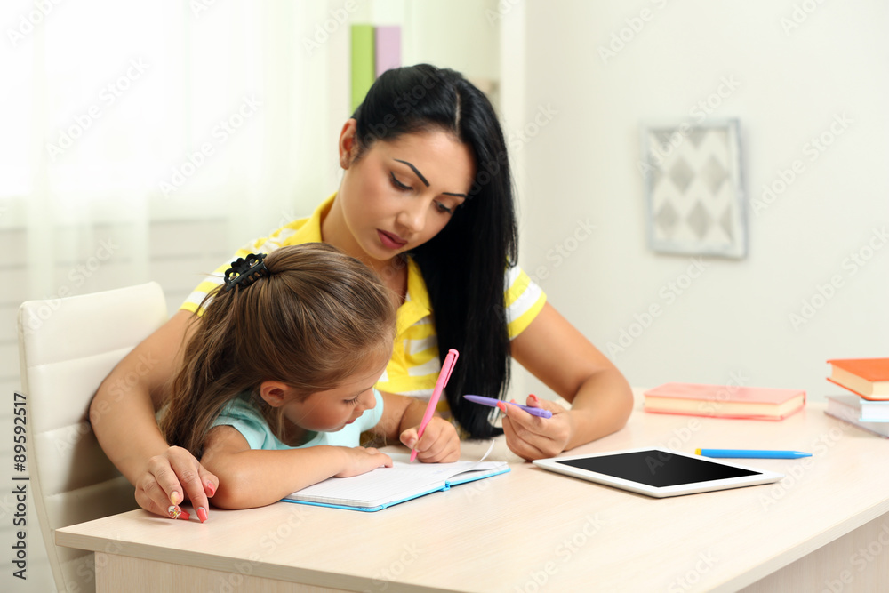 Beautiful school girl doing homework with mother at home Beautiful school girl doing homework with mother at home