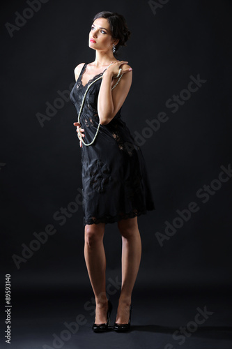 Retro style photo of young woman with beads on dark background