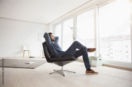 Young man relaxing on leather chair in his living room photo