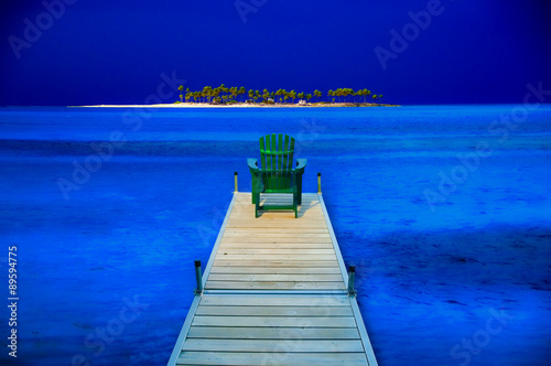 Adirondack chair sitting on the end of dock surrounded by deep b