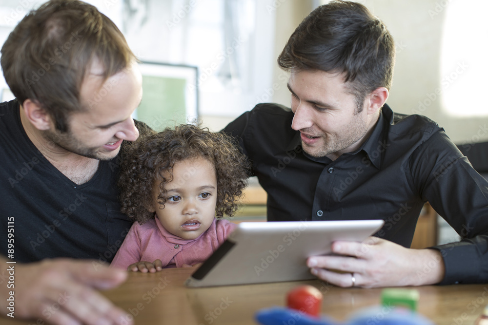 Two men with kid looking at digital tablet Two men with kid looking at digital tablet