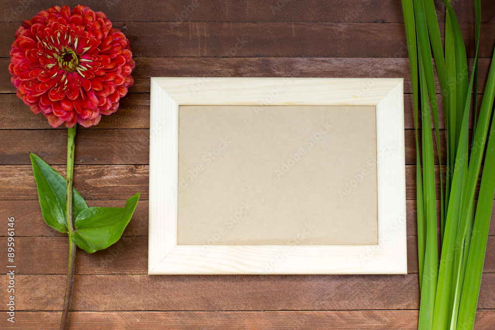 empty picture frame on wooden background, zinnia flowers