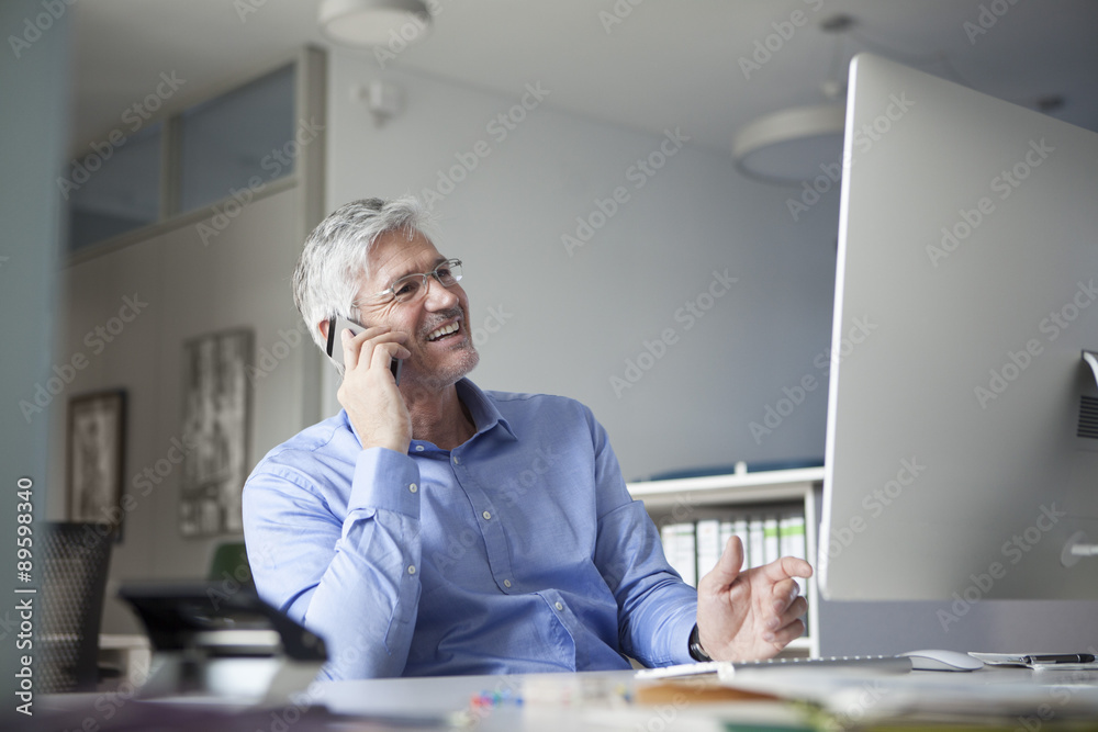 Businessman sitting at desk, talking on the phone Businessman sitting at desk, talking on the phone