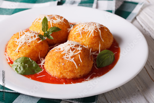 Delicious fried arancini rice balls in tomato sauce close-up. horizontal 