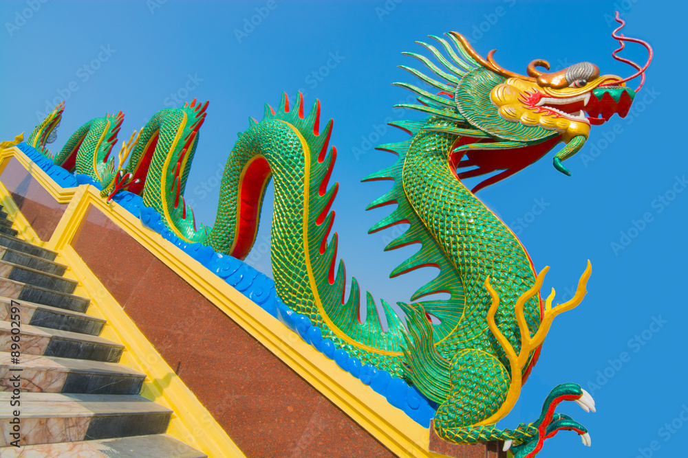 Chinese dragon guardian on stairway against blue sky background.