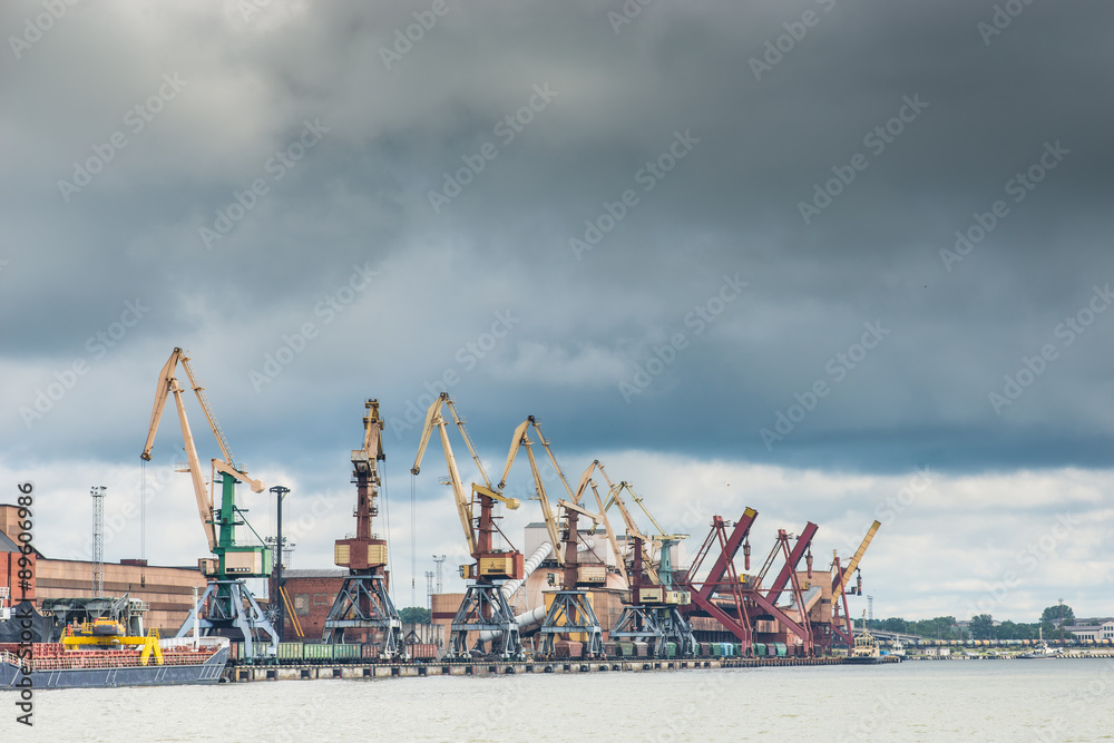 Cargo cranes and railway cars in the port under the stormy sky