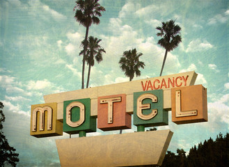 Aged and worn vintage photo of retro motel sign with palm trees