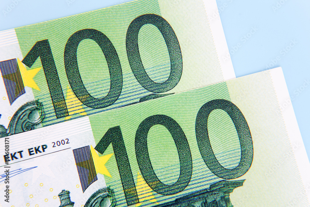 Two 100 euro notes on light blue background Two 100 euro notes on light blue background