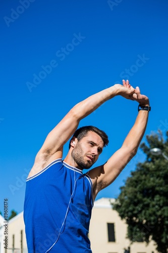 Handsome athlete stretching against blue sky