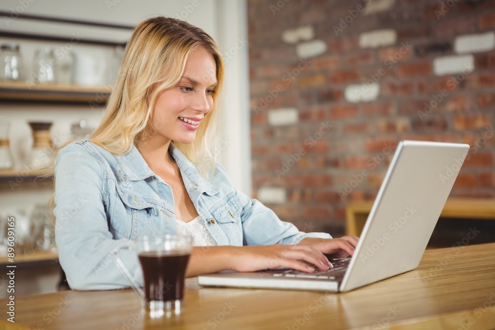 Smiling blonde having coffee and using laptop Smiling blonde having coffee and using laptop