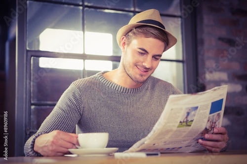 Handsome hipster having coffee and reading newspaper