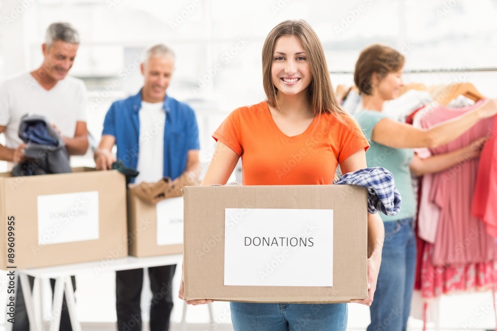 Smiling casual businesswoman holding donation box Smiling casual businesswoman holding donation box