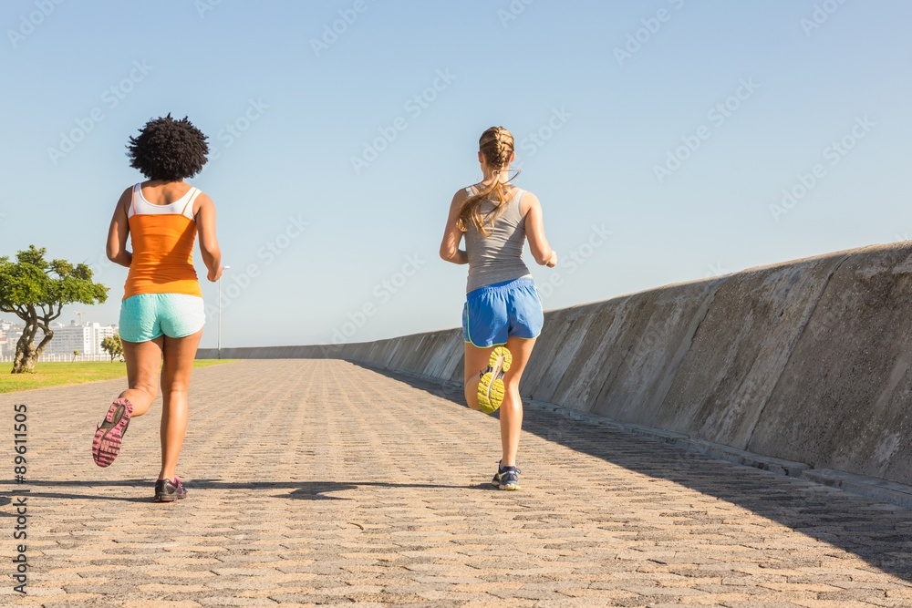 Rear view of two young women jogging together Rear view of two young women jogging together
