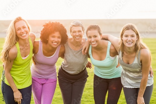 Smiling sporty women with arms around each other