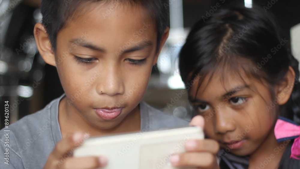 Brother and sister having fun with game in smartphone Brother and sister having fun with game in smartphone