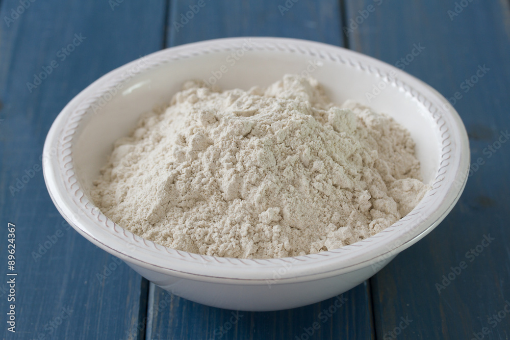 powder on white plate on blue wooden background powder on white plate on blue wooden background