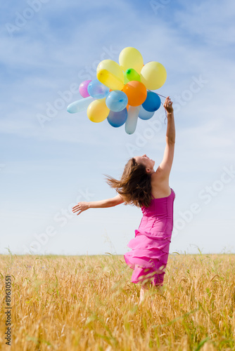 young woman holding air balloons on summer blue sky 