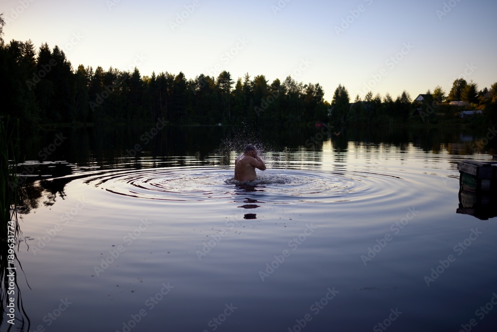 Adult man splash water in forest lake