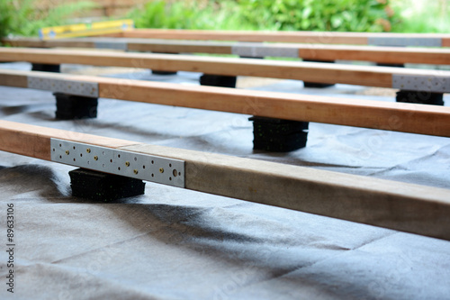 Unterkonstruktion für Terrasse mit Holzbalken und Terrassenpads aus Granulat und Bautenschutzmatte