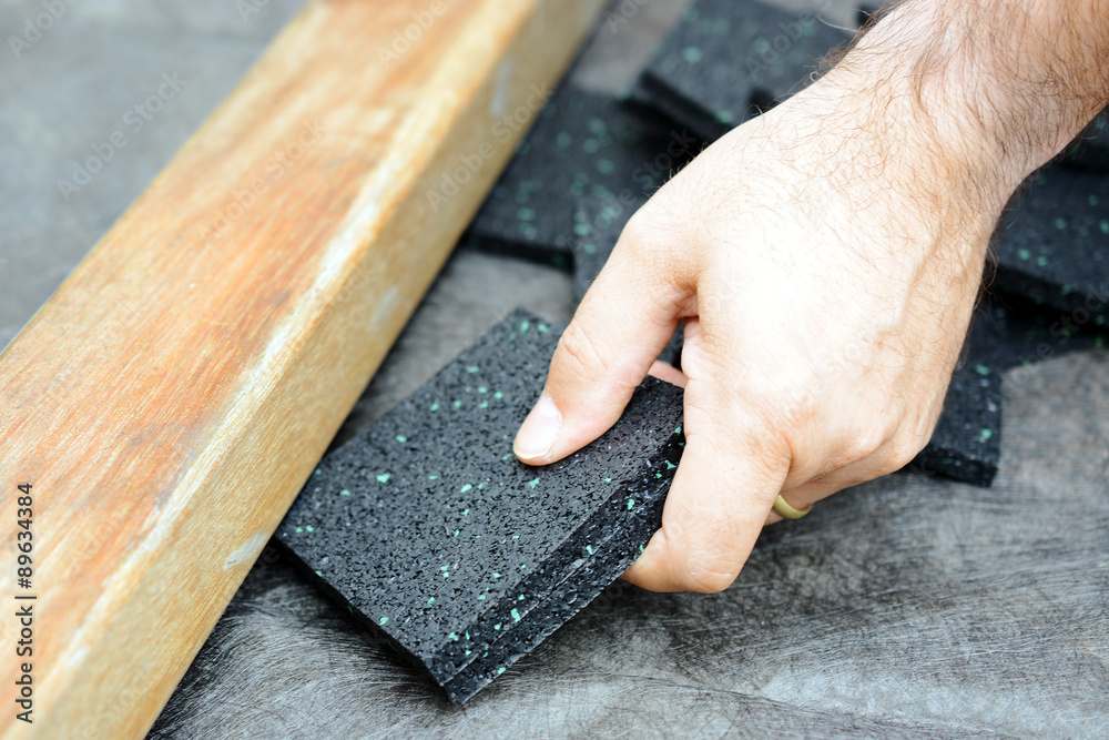 Schreiner oder Handwerker setzt Granulatpad aus Bautenschutzmatte unter  Holzbalken für Terrasse Stock-Foto
