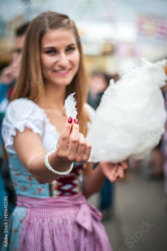 Attractive young woman wearing a traditional Dirndl dress with cotton candy floss at the Oktoberfest. photo