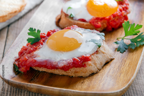 fried eggs with tomato sauce on bruschetta