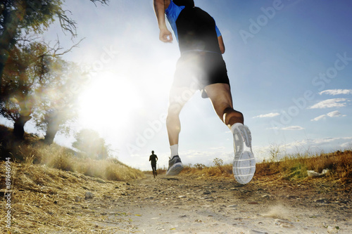 Silhouette of young sport man running off road cross country competition at summer sunset