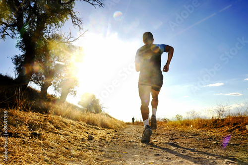 Silhouette of young sport man running off road cross country competition at summer sunset photo