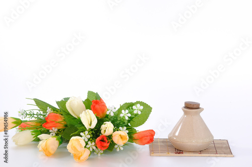 Colorful flower pot with small bottle on bamboo mat.