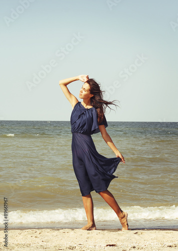 Young beautiful woman at seaside in blue dress