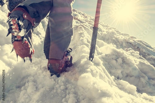 Close up of hiking shoes with crampons and ice axe. photo