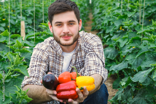 Young handsome photogenic guy is working in a greenhouse.
