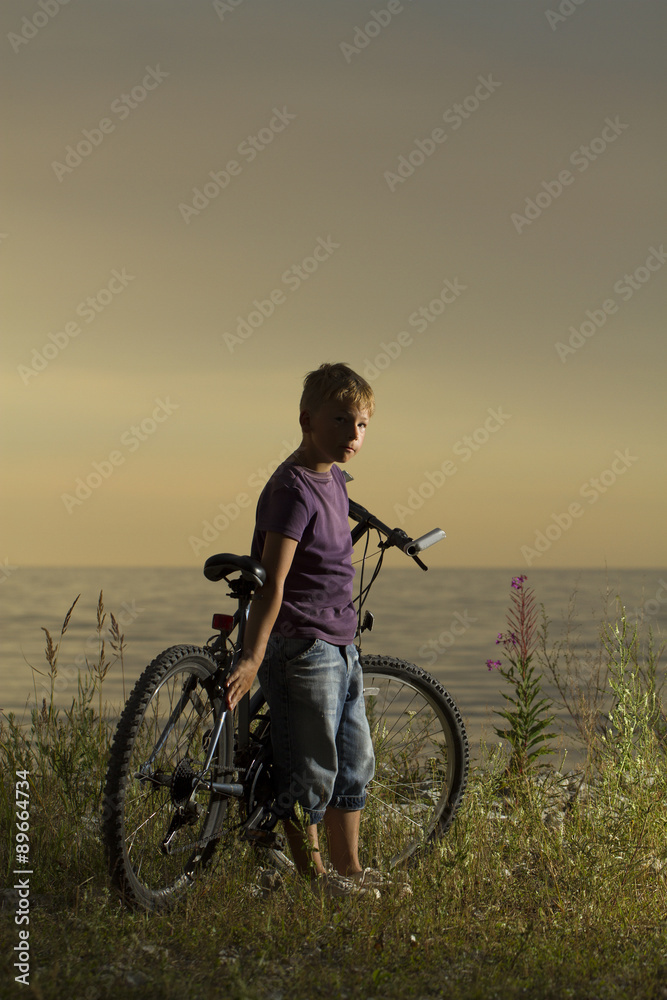 boy on a bicycle near the sea in the evening at sunset.