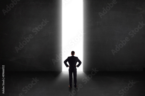 Business person looking at wall with light tunnel opening