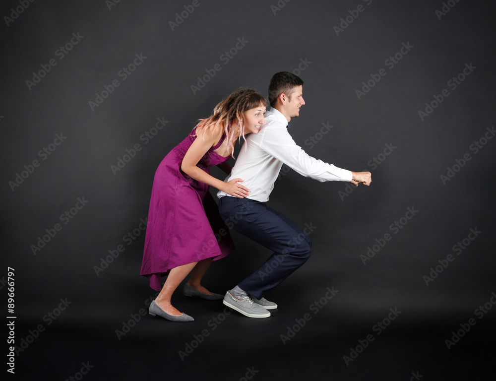 Funny young couple on black background